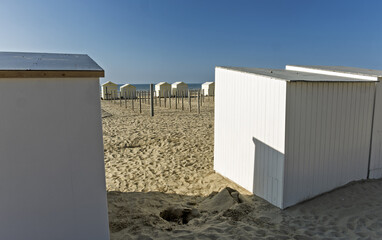 Row of white beach huts at sunset at De Panne, Belgium.