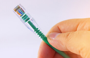 The hand is holding a wire with an Rj45 connector to connect the Internet. 
