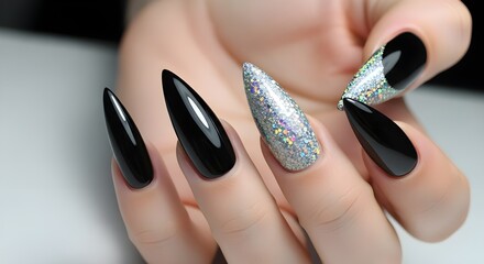 Close up of a woman's hand with black and glittery silver stiletto nails