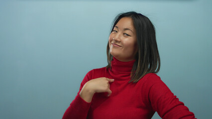Woman pointing at herself with confidence wearing red sweater against isolated blue background...