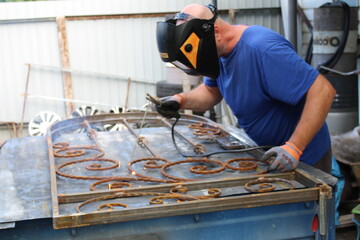 the man works as a welder, makes beautiful gates