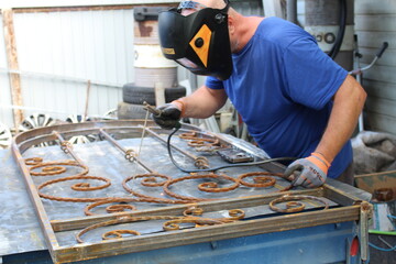 the man works as a welder, makes beautiful gates