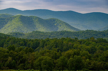 Fototapeta premium Fading and dappled light from a stormy sky strikes three ridges of the Smoky Mountains in Cades Cove, Tennessee