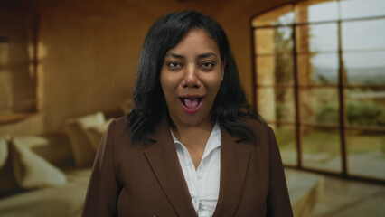 African american woman with open mouth speaking in living room looking at camera; friendly...