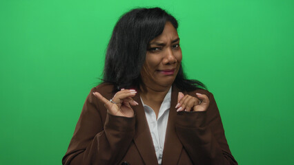 Woman grimaces and pushes palms outward wearing a brown blazer and white shirt in a studio on...