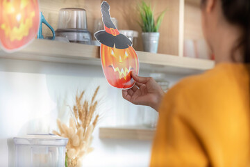 Halloween Decor. Woman placing a pumpkin decoration on a shelf for festive spirit.