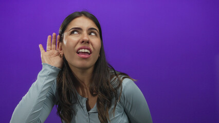 Young hispanic woman listening intently on a purple isolated background, showing curiosity and...