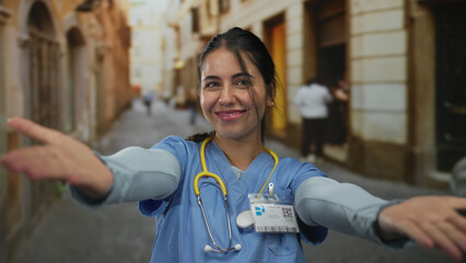 Young hispanic woman doctor wearing blue uniform and stethoscope stretches arms to camera on a...