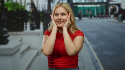 Young blonde woman smiling confidently on a city street in casual red shirt enjoying outdoors