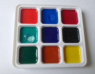 Overhead view of an artist's palette filled with vibrant, semi-dried watercolor pigments