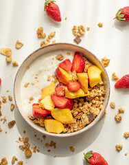 Granola or muesli with natural greek yogurt, strawberry and peach in a bowl and scattered on a...