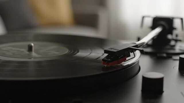 Vinyl Record Player Close-up - A close-up shot focuses on the needle of a vinyl record player as it plays a black record. The modern turntable sits on a surface, subtly blurred in the background.