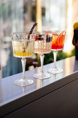 Colorful cocktails with fresh citrus fruits on bar counter
Three elegant cocktails with ice and garnishes displayed between buckets of fresh oranges and lemons on a stylish outdoor bar counter.
