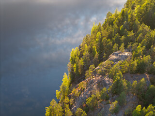 Beautiful aerial view of rocky lake with reflection of clouds on a summer evening.