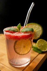 Watermelon cocktail with mint and lime on a wooden board, dark background
