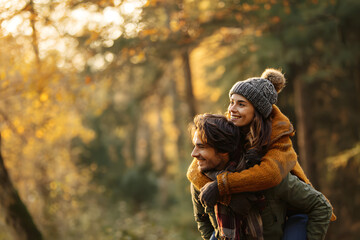 Fototapeta premium Happy couple piggybacking in a forest one autumn afternoon