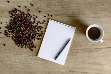 Morning brew and fresh ideas — coffee beans, notebook and pen on desk