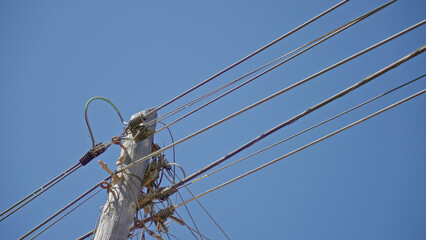 Electric wooden pole with wires against clear blue sky, capturing the essence of utility...