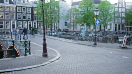 Blurred street scene in amsterdam shows defocused cityscape with bokeh effect, featuring canals and...