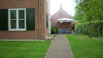 Blurry house exterior with green garden and patio furniture showcasing tranquil outdoor living space.