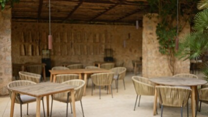 Blurry terrace scene with defocused chairs and tables in a mediterranean-style restaurant featuring warm tones and bokeh effect for a relaxed dining atmosphere.