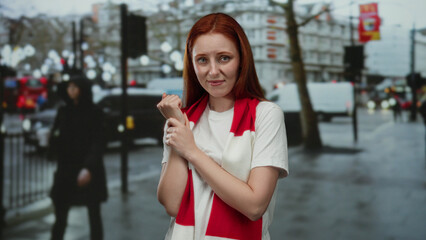 Woman with red hair wearing red scarf is seen standing on a busy city street appearing distressed...