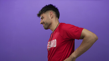 Lifeguard man wearing red shirt and whistle holding lower back for backache in studio side view;...