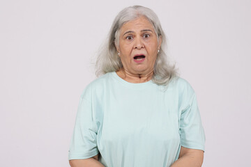 Portrait of a indian shocked and scared old woman posing against a white background