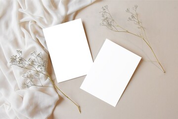 Two white blank cards on beige satin fabric with dry plant decor