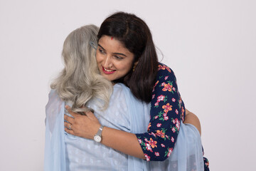 Indian smiling young daughter and old mother hug embrace isolated on white studio background....
