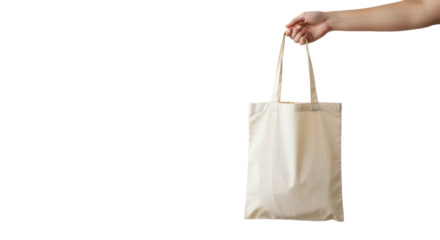 Light-skinned hand gently presents an empty, unbranded canvas tote bag in soft high-key studio light with negative space, concept of sustainable living
