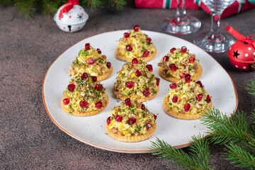 Appetizer on crackers of melted cheese, walnuts and pomegranate in shape of Christmas trees