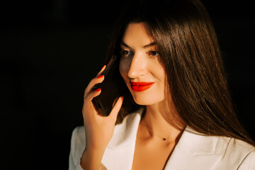 Young woman with long hair and red lips enjoys a moment in soft light during the evening