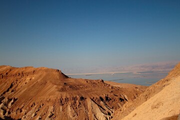 Warm sunset glow over rugged cliffs near the Dead Sea, highlighting the contrast between golden light and arid terrain.