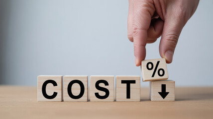 A hand is seen lowering a cube with a percentage symbol, symbolizing cost reduction