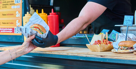 Close-up of customer grabbing a hamburger during a hamburger food truck festival.