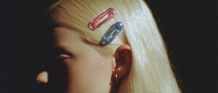 Primo piano di una ragazza bionda con forcine colorate nei capelli, stile retr&ograve;