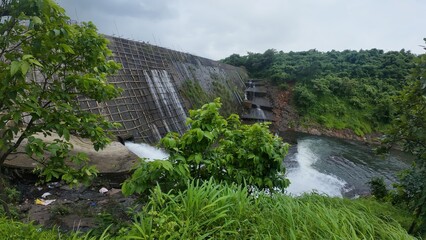 Obraz premium Powerful Water Release from Dam Spillway Under Bright Cloudy Sky