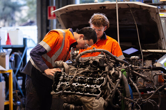 Two male mechanics inspecting vehicles engine in workshop