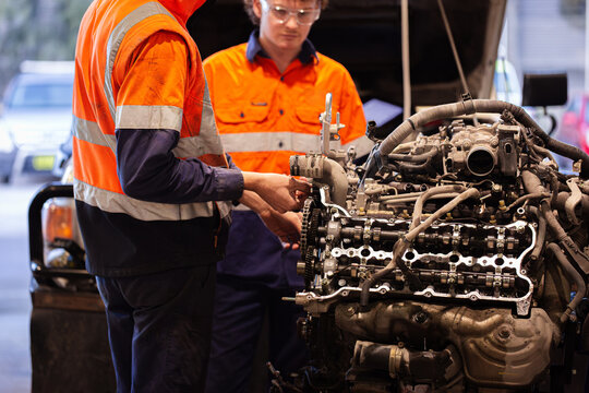 Two male mechanics inspecting vehicles engine in workshop