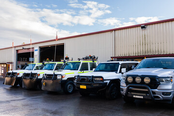 Fleet of white utility vehicles lined up outside mechanics repair shed