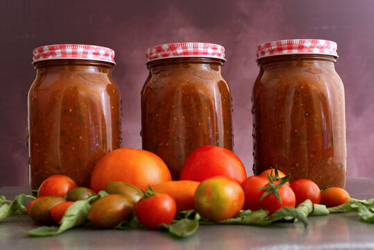 Jars of Tomato Sauce with Fresh Tomatoes and Basil on a Rustic Background