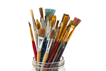 Variety of artist paintbrushes in a clear jar isolated on black background for creative purposes