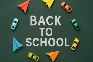 Back to school text on chalkboard surrounded by colorful paper planes and toy cars arranged in circle, creating playful education theme