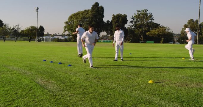 Tapping stopwatch, diverse male sports team performing agility drills at sports field for warm-up