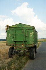 A farmer's large green dump trailer stands in a field. The picture shows the start of the harvest...