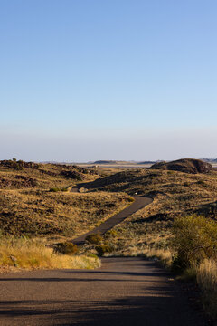 narrow bitumen road winding through undulating landscape near Cossack in the pilbara