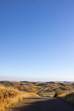 vertical image with copy space in blue sky over pilbara landscape featuring winding road at cossack