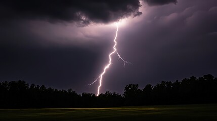 Bright lightning strike over dark forest and field during night thunderstorm