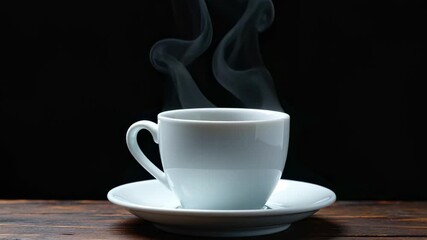 A white cup of hot coffee or tea with steam rising, on a wooden table against a black background. - Powered by Adobe